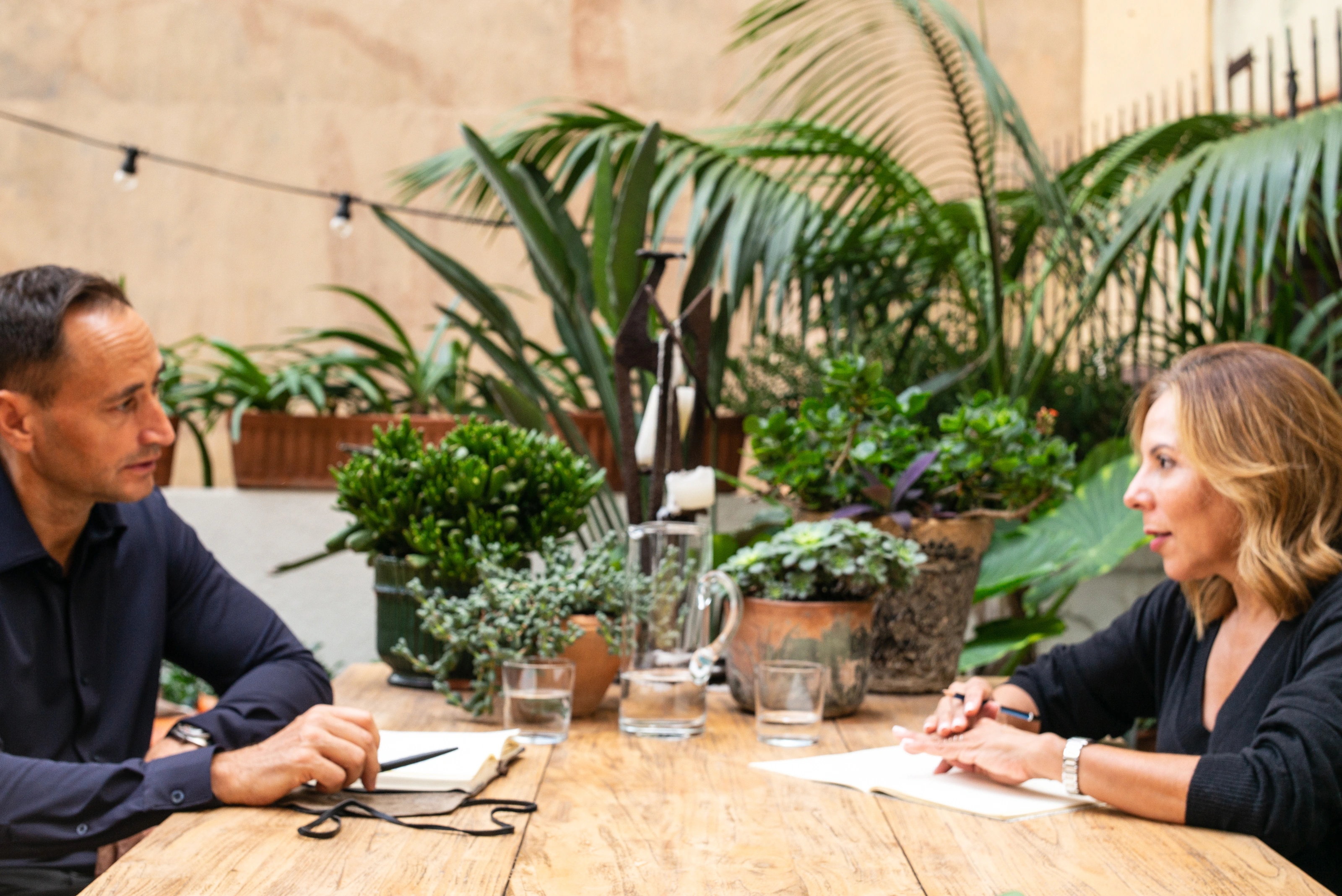 John-Oliver Breckoff in a coaching conversation at a table surrounded by plants