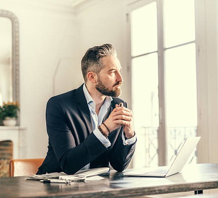 An executive pausing by a bright window, lost in thought